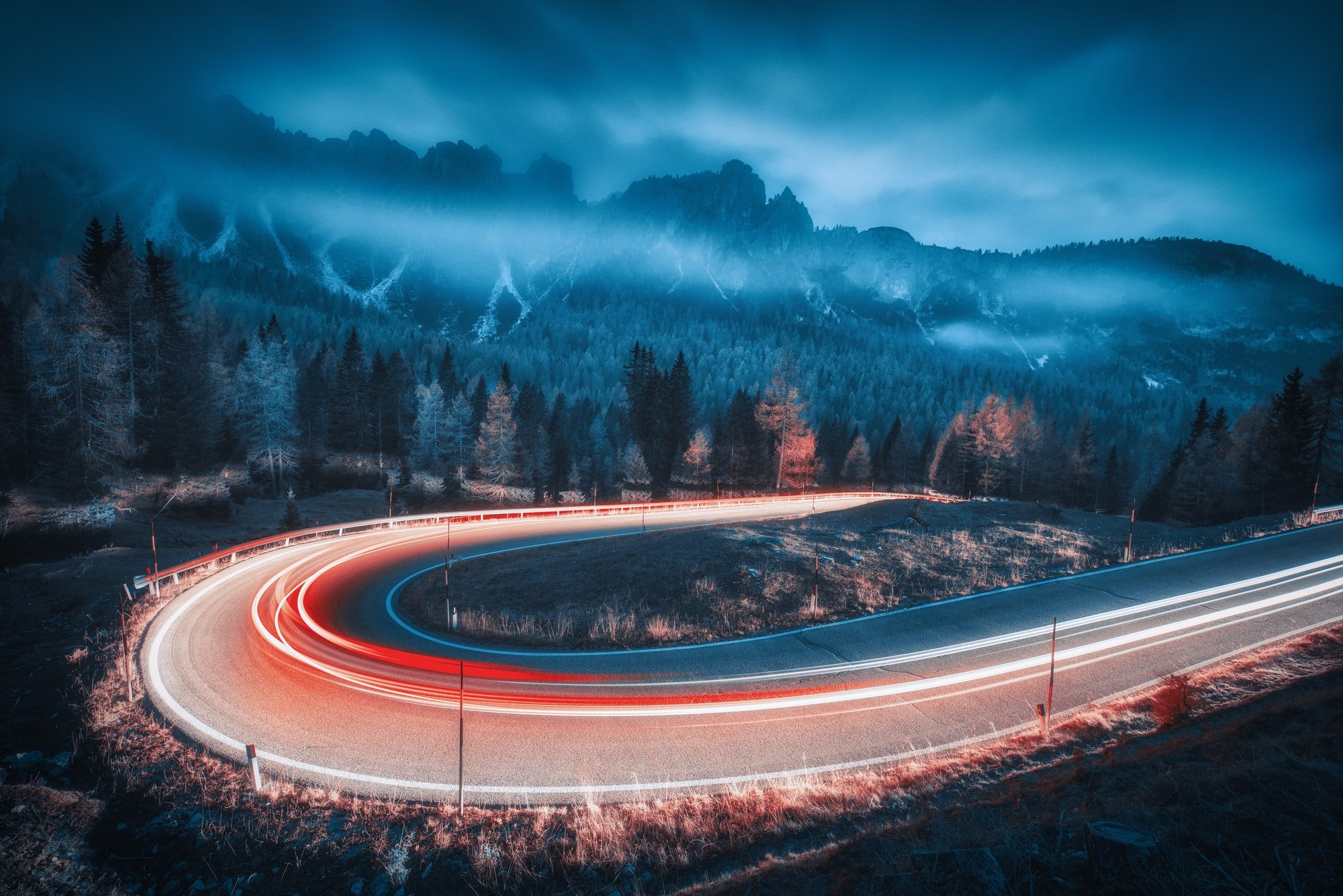 Blurred car headlights on winding road in mountains